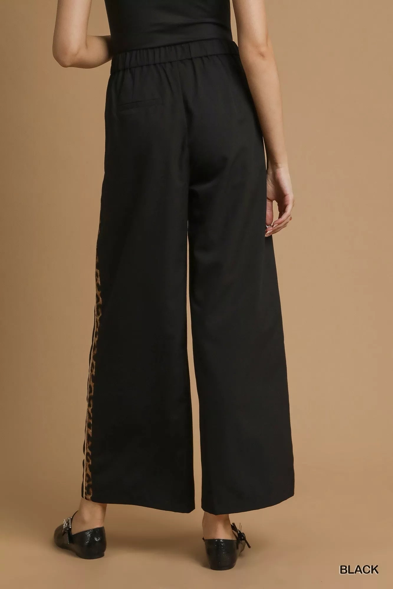 Black wide-leg pants with a side slit on a brown background