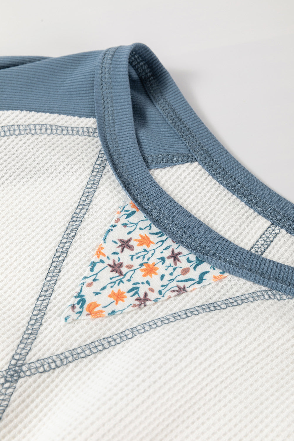 Close-up of a textured fabric with floral pattern and blue trim on a white background